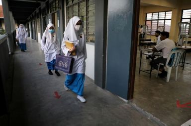 FILE PHOTO: Students wearing protective masks walk past a classroom