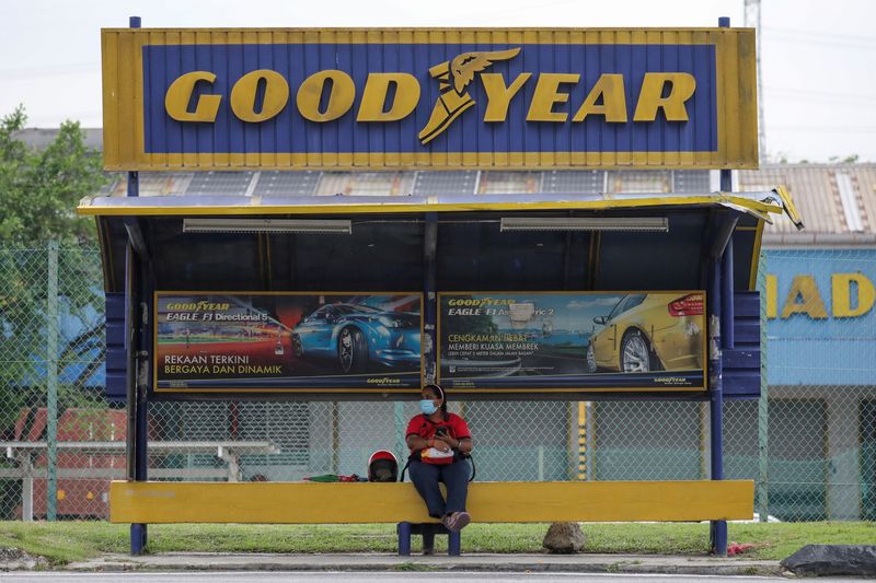 A woman sits at a bus stop outside Goodyear factory