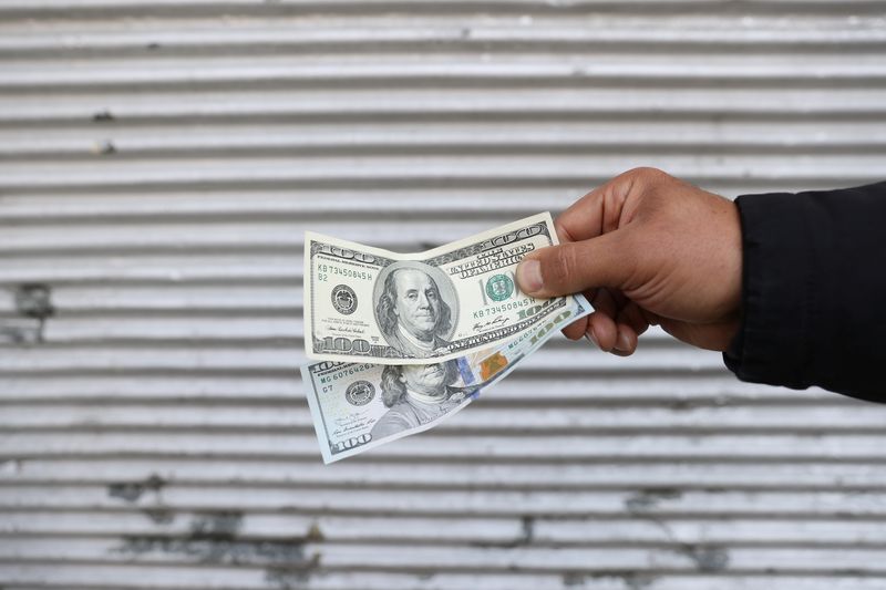 A street-side currency vendor holds U.S. dollars at Ferdowsi Square