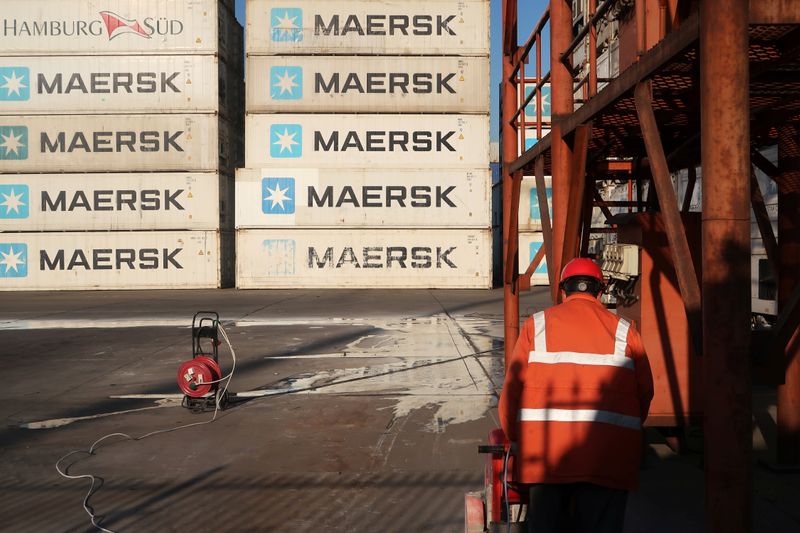 Worker is seen next to Maersk shipping containers at a