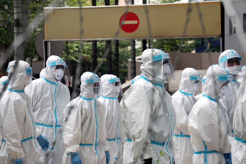 Police officers wearing protective suits gather outside an apartment under